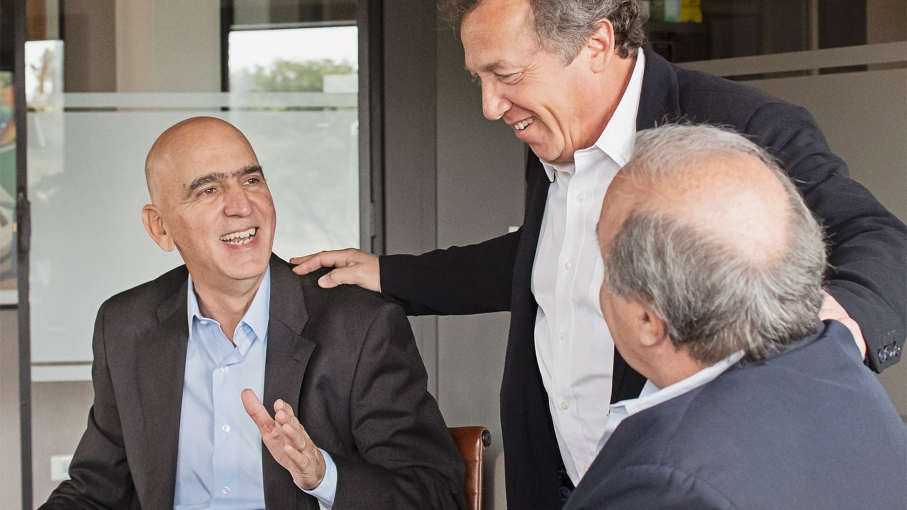 Tres socios de Greenback Capital conversando en la oficina
